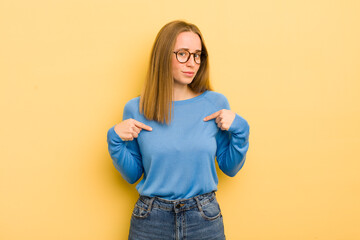 pretty caucasian woman looking proud, positive and casual pointing to chest with both hands