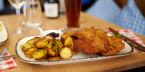 Saftiger Wiener Schnitzel vom Kalb mit wellen Panade und Bratkartoffeln auf schönem Teller 