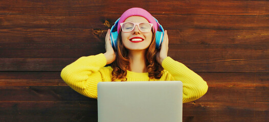 Portrait of modern happy smiling young woman relaxing and enjoying listening to music in headphones...