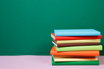 Composition with vintage old hardback books, diary, fanned pages on wooden deck table and colored background. Books stacking. Back to school. Copy Space. Education background.