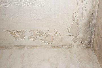 Discoloured peeling paint on the ceiling in a corner of a room requiring repair and renovation to...