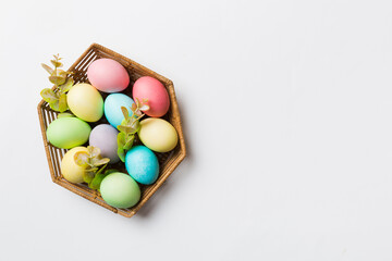 Multi colors Easter eggs in the woven basket on colored background . Pastel color Easter eggs. holiday concept with copy space