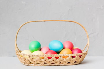Multi colors Easter eggs in the woven basket on colored background . Pastel color Easter eggs....