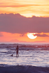 Sunrise sky with stand up paddle boarder in the ocean. Gold Coast, Australia