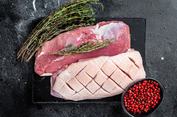 Raw Duck breast, fillet poultry meat steaks with herbs. Black background. Top view