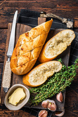 Toasted Garlic bread with herbs and butter on wooden cutting board. Wooden background. Top view