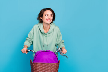 Photo of dreamy shiny woman wear green sweatshirt driving cycle rucksack empty space isolated blue...