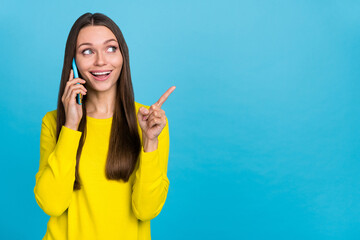 Photo of impressed millennial brunette lady talk telephone indicate promo wear yellow shirt isolated on blue background