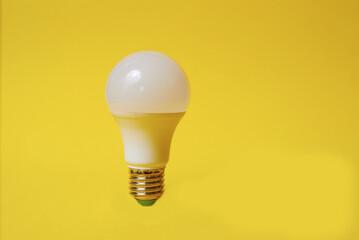White led light bulb on yellow background
