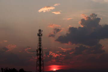 Telecommunication tower silhouette during sunset with pastel sky background. Concept of digital infrastructure, wireless communication, mobile network, and 5G technology