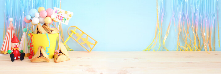 Purim celebration concept (jewish carnival holiday) over purple wooden table and pastel blue background