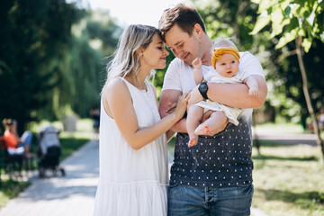 Obraz premium Young couple with their baby daughter in park