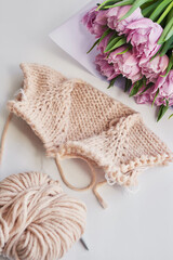 Knitted kids clothes and accessories for knitting. Needlework and knitting. Hobbies and creativity. Knit for children. Handmade. Pink sweater and tulips