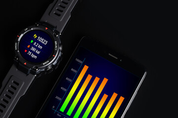 Black smart watch on the smartphone. Closeup, selective focus. All screen graphics are made up
