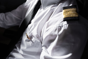 sunshine on badge and uniform on professional pilot in airplane. © LIGHTFIELD STUDIOS