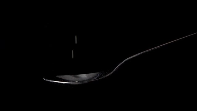 Measuring one tablespoon cane or brown sugar powder on a spoon, black background