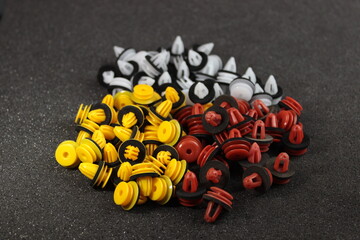 Macro photography of plastic multi-colored clips for a car on a gray background. Car clips, plastic fasteners, multicolored plastic clips on a gray background close-up.Car clips and fasteners.
