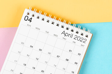 April 2022 desk calendar on multicolored background.