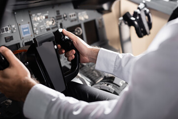 partial view of pilot using yoke in airplane simulator.