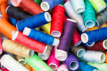 Heap of spools of colorful sewing threads, texture multicolored thread