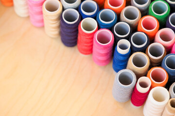 Multicolor sewing threads on wooden background. Yarn on a spool, yarn on a tube, cotton thread