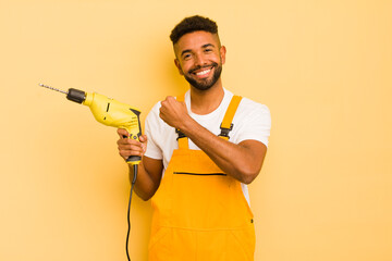 afro cool man feeling happy and facing a challenge or celebrating. handyman and drill concept