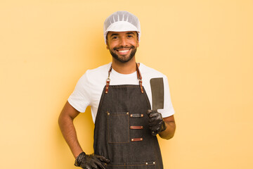afro cool man smiling happily with a hand on hip and confident. butcher concept