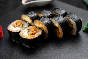 sushi rolls laid out on a dark background decorated with bamboo leaves and chopsticks