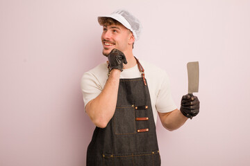 young cool man smiling with a happy, confident expression with hand on chin. butcher concept