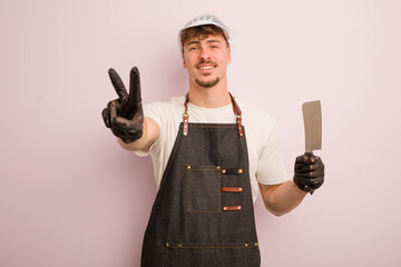 young cool man smiling and looking happy, gesturing victory or peace. butcher concept