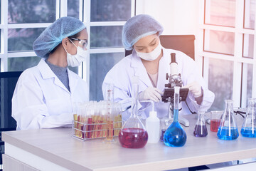 Laboratory two woman scientists Conduct Experiments. Chief Research Scientist Adjusts Specimen in a Petri Dish and Looks on it Into Microscope.
