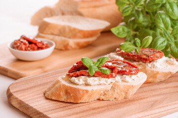 Classic italian appetizer - bruschettas or toasts with ricotta cheese and sliced sun dried tomatoes topped with basil on wooden table background. Delicious appetizer