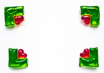 Washing capsules on a white background. Liquid laundry detergent in red-green heart-shaped capsules.