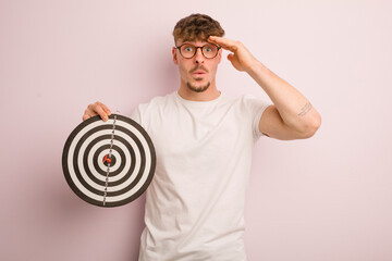 young cool man looking happy, astonished and surprised. dart target concept