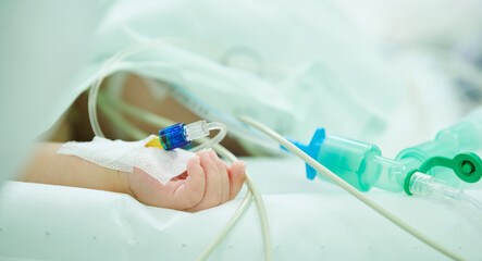 Children surgery. Small hand with saline intravenous dropper during surgical operation in hospital