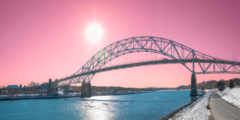 Sagamore Bridge over Cape Cod Canal with the glowing sun at pink sunset