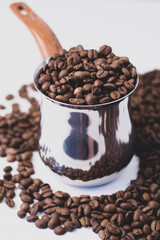 fragrant beans from the coffee tree in medium roast lie on a white background with space for text in an iron coffee maker with a brown handle