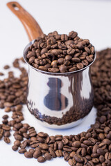 fragrant beans from the coffee tree in medium roast lie on a white background with space for text in an iron coffee maker with a brown handle