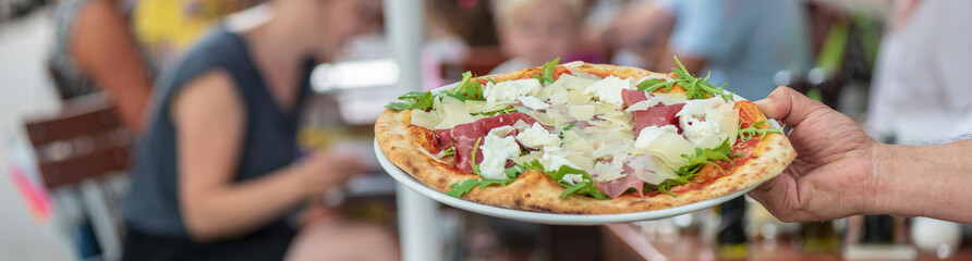 frische italienische Pizza aus dem Ofen in der Hand im Restaurant 