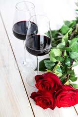 romantic dinner. Two glasses of wine with roses and petals.