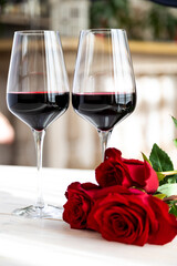 romantic dinner. Two glasses of wine with roses and petals.