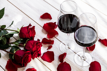 Fototapeta na wymiar romantic dinner. Two glasses of wine with roses and petals.