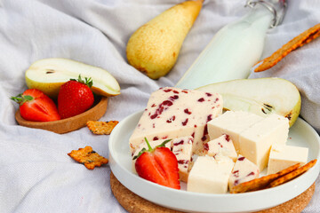 Summer picnic with Wensleydale cheese and cheddar cheese, Strawberries, pears and milk on the cork kitchen stands and grey fabric