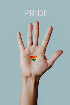 raised hand with a heart-shaped rainbow pride flag