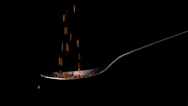Instant coffee granulate falling in slow motion on spoon isolated background