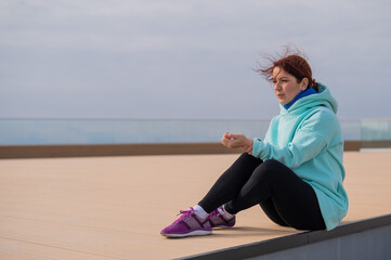 Caucasian woman in a sweatshirt measures her pulse after jogging. 