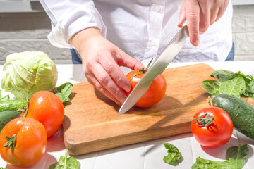 Close-up of cutting slicing fresh tomatoes. Womans hands cut with knife fresh tomato vegetables