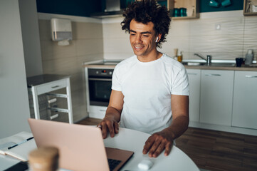 African american man using laptop in the kitchen at home