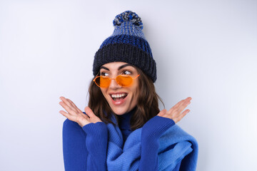 Young woman in a blue golf turtleneck, hat and scarf, sunglasses, on a white background, cheerful...