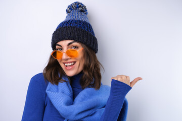 Young woman in a blue golf turtleneck, hat and scarf, sunglasses, on a white background, cheerful...